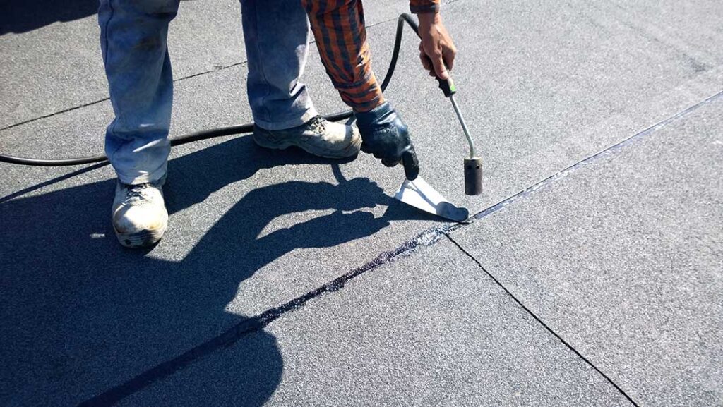 Homeowner examines attic insulation beneath roof decking during a winter inspection.