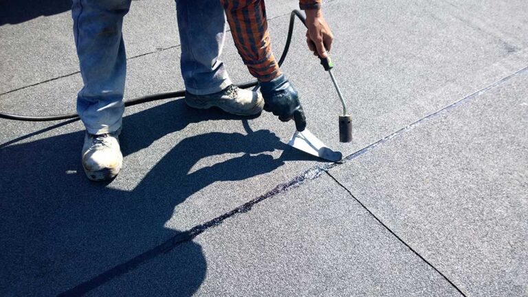 Homeowner examines attic insulation beneath roof decking during a winter inspection.